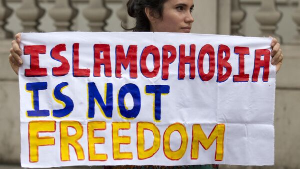 Женщина держит плакат с надписью Исламофобия - это не свобода - Sputnik Азербайджан