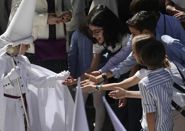 Ребёнок раздаёт конфеты другим детям во время шествия в Вербное воскресенье в Севилье, Испания. - Sputnik Азербайджан
