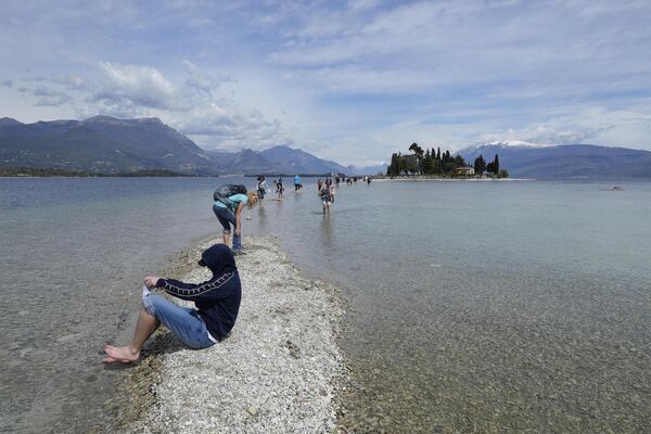 Туристы пересекают участок между материком и островом Сан-Бьяджо на озере Гарда. - Sputnik Азербайджан