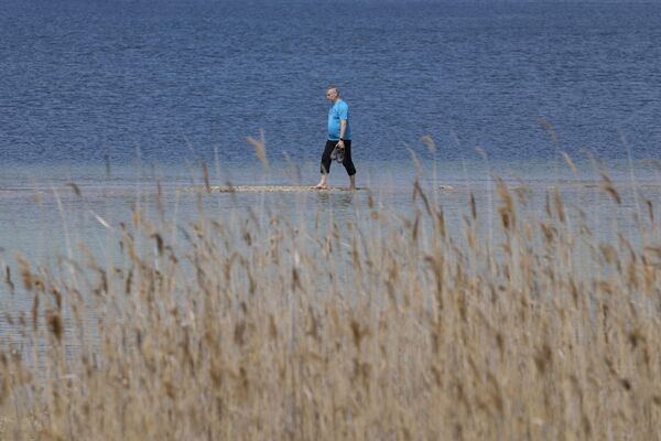Турист идет по участку между материком и островом Сан-Бьяджо на озере Гарда. - Sputnik Азербайджан