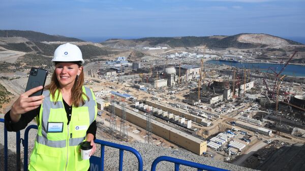 Женщина фотографируется на фоне строящейся атомной электростанции Аккую в турецком городе Гюльнар - Sputnik Азербайджан