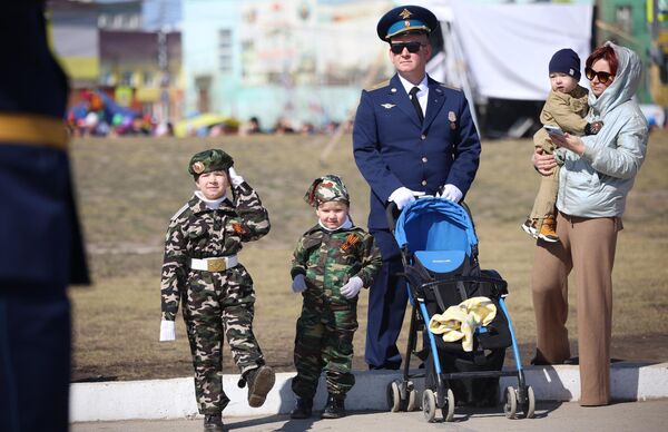 Военнослужащий с семьей наблюдают за военным парадом, посвященном 78-й годовщине Победы в Великой Отечественной войне, в Якутске - Sputnik Азербайджан