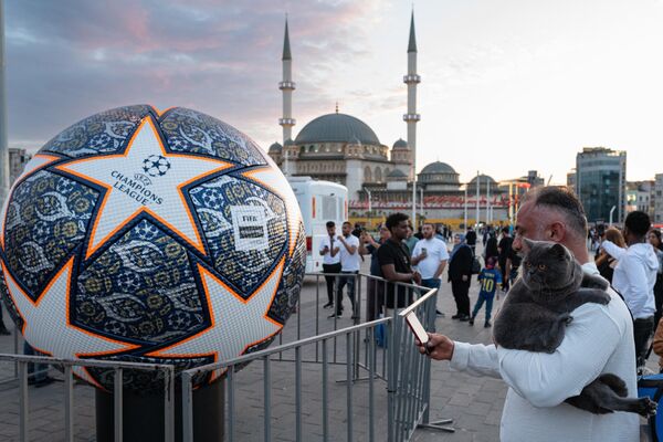 İstanbulun Taksim meydanında kişi Çempionlar Liqası futbol topunun maketinin şəklini çəkir. - Sputnik Azərbaycan