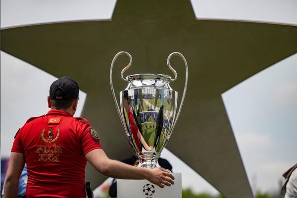 Мужчина фотографируется с кубком Лиги чемпионов УЕФА. - Sputnik Азербайджан