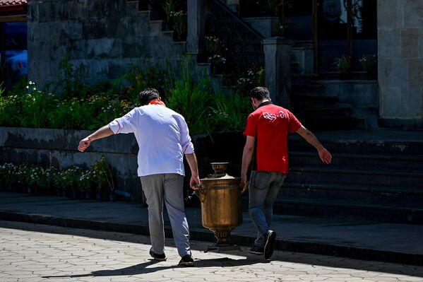 Сотрудники ресторана несут большой самовар на улице в Шуше. - Sputnik Азербайджан