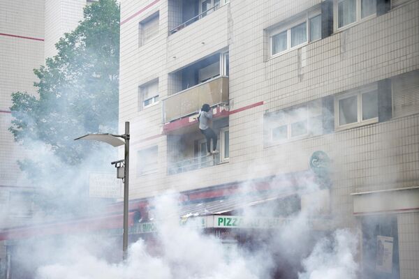 Протестующий взбирается на здание во время столкновений, вспыхнувших после марша в память о подростке-водителе, застреленном полицейским, в парижском пригороде Нантер. - Sputnik Азербайджан