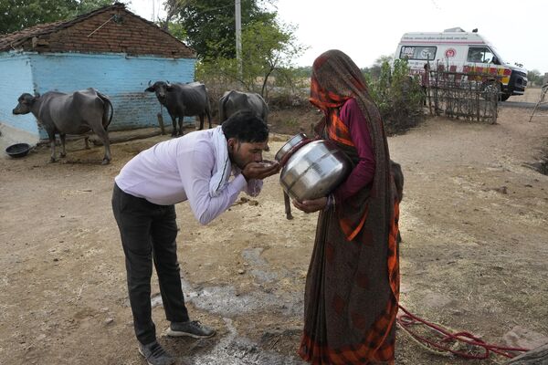 Hindistanın Uttar-Pradeş ştatının Banpur kəndi yaxınlığında kənd sakini xəstəxanaya gedən təcili yardımın sürücüsünə su verir. - Sputnik Azərbaycan