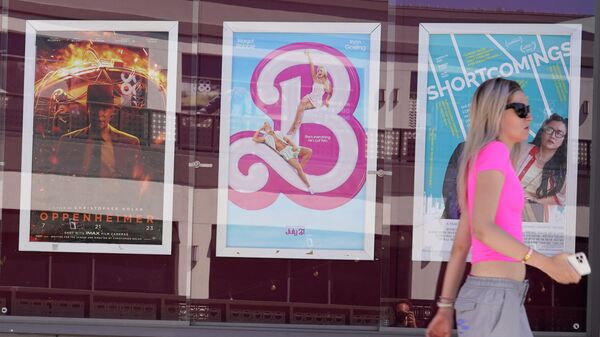 Женщина проходит мимо рекламы фильмов «Оппенгеймер» (слева направо) и «Барби» - Sputnik Азербайджан