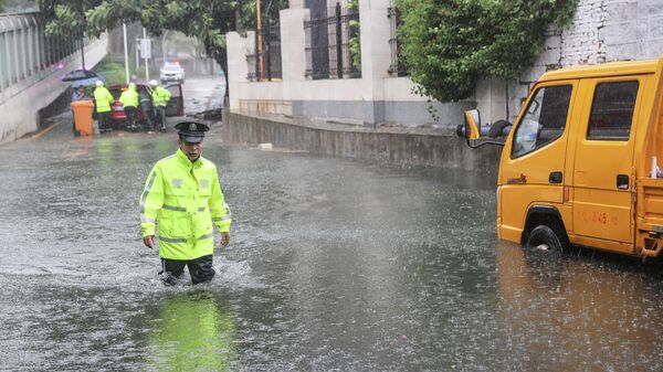Полицейский идет по затопленной улице в Китае - Sputnik Азербайджан
