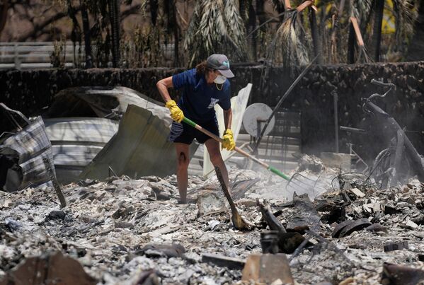 Женщина копается в развалинах дома, разрушенного лесным пожаром в Лахайне. - Sputnik Азербайджан