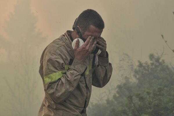 Пожарный вытирает глаза во время лесного пожара недалеко от Продромоса, Греция. - Sputnik Азербайджан