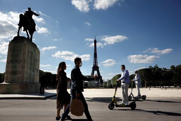 Люди едут на электросамокате мимо статуи маршала Жоффра на фоне Эйфелевой башни в Париже. - Sputnik Азербайджан