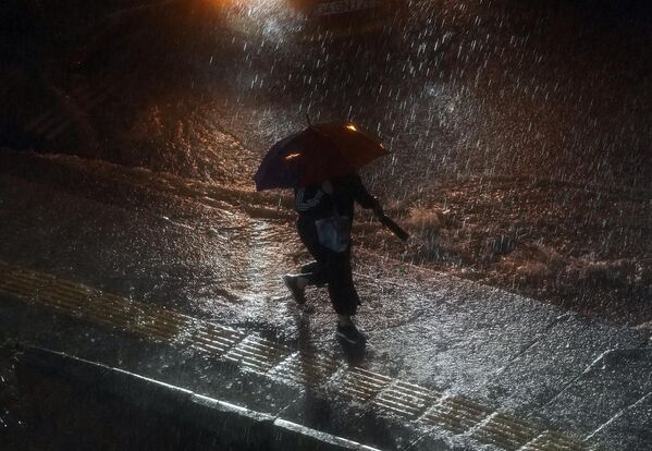 Женщина во время прогулки под дождем в районе Башакшехир в Стамбуле, Турция. - Sputnik Азербайджан
