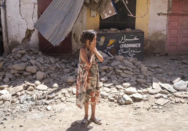 Ребенок перед своим поврежденным в результате землетрясения домом в городе Амизмиз. - Sputnik Азербайджан