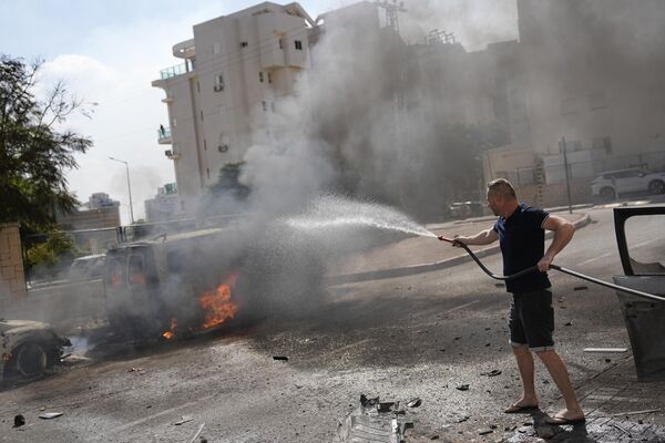 Машины горят после ракетного обстрела из сектора Газа в Ашкелоне, на юге Израиля. - Sputnik Азербайджан
