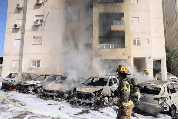 Бригады израильских пожарных тушат пожар на стоянке возле жилого дома после ракетного обстрела из сектора Газа в городе Ашкелон. - Sputnik Азербайджан