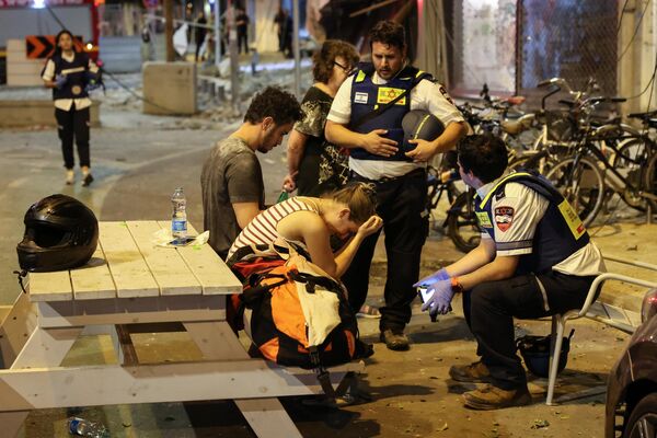 Женщина разговаривает с израильскими спасателями в Тель-Авиве после ракетного обстрела. - Sputnik Азербайджан