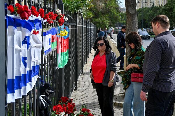 Люди несут цветы к израильскому посольству в Баку после атаки движения ХАМАС на Израиль. - Sputnik Азербайджан