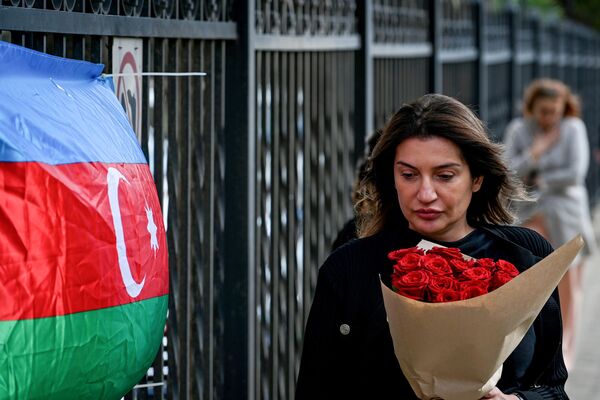 Люди несут цветы к израильскому посольству в Баку после атаки движения ХАМАС на Израиль. - Sputnik Азербайджан
