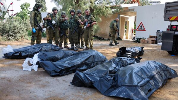 Израильские солдаты готовятся вынести тела своих соотечественников, погибших во время нападения палестинских боевиков, в Кфар-Азе, к югу от Израиля - Sputnik Азербайджан