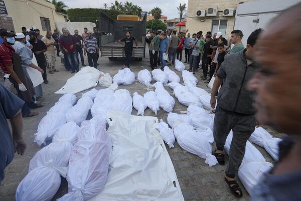 Палестинцы стоят вокруг тел людей, погибших в результате израильской бомбардировки сектора Газа. - Sputnik Азербайджан