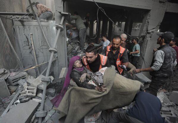 Палестинские спасатели эвакуируют раненую женщину, которая была найдена под обломками разрушенного дома после израильского авиаудара. - Sputnik Азербайджан