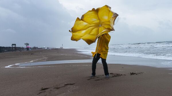 Мужчина с зонтом на пляже в ветреную погоду - Sputnik Azərbaycan