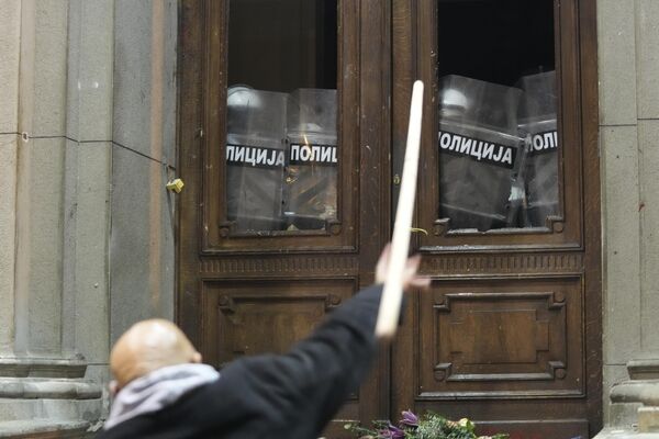 Протестующий бросает палку в здание мэрии Белграда. - Sputnik Азербайджан