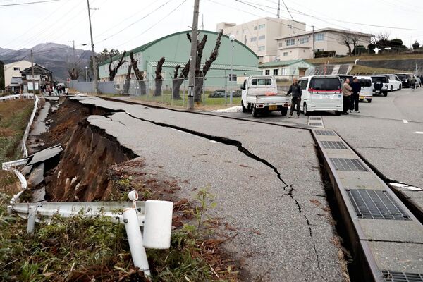 Люди стоят возле разрушенной в результате землетрясения дороги в городе Вадзима, префектура Исикава, Япония. - Sputnik Азербайджан