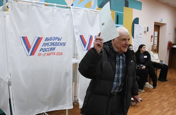 Мужчина голосует на выборах президента России на избирательном участке №4127 во Владивостоке - Sputnik Азербайджан