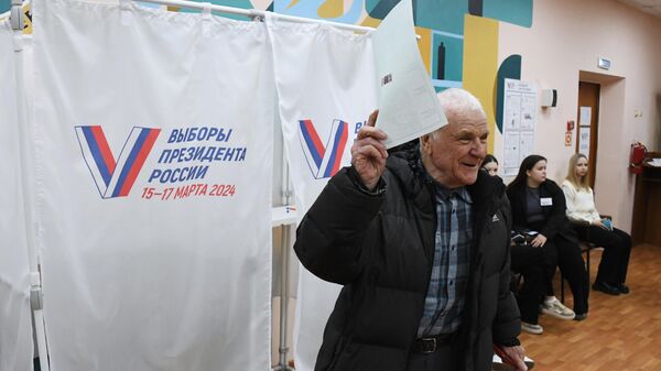Мужчина голосует на выборах президента России на избирательном участке №4127 во Владивостоке - Sputnik Азербайджан
