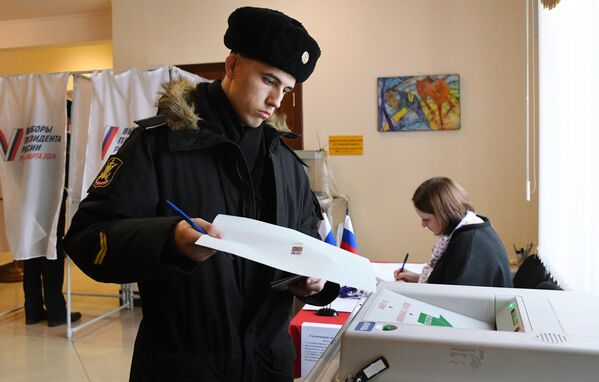 Военнослужащий Тихоокеанского флота голосует на выборах президента России на избирательном участке №502 во Владивостоке - Sputnik Азербайджан