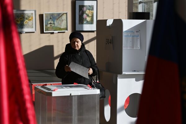 Женщина голосует на выборах президента России на избирательном участке в Москве - Sputnik Азербайджан