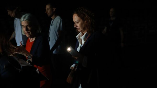 Люди используют свои телефонные фонарики, чтобы пройти по темным проходам во время общего отключения электроэнергии в седьмой день Mutua Madrid Open - Sputnik Азербайджан