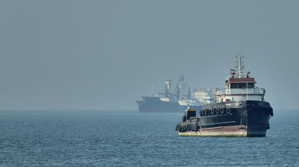 Иранский буксир плавает на переднем плане, в то время как грузовые суда стоят на якоре в Ормузском проливе - Sputnik Азербайджан