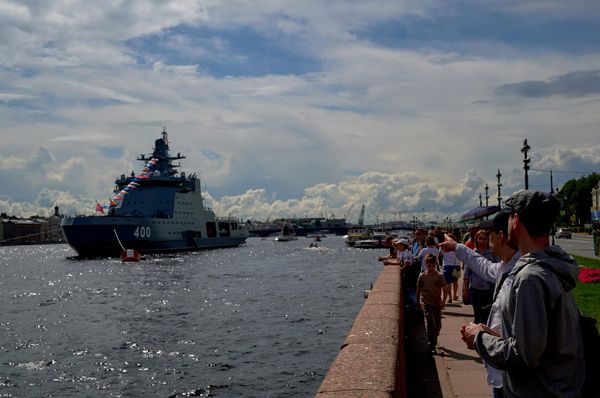 Зрители на набережной смотрят на проход кораблей в акватории Невы в преддверии Дня ВМФ в Санкт-Петербурге. Слева: патрульный корабль ледового класса "Иван Папанин" проекта 23550 - Sputnik Азербайджан
