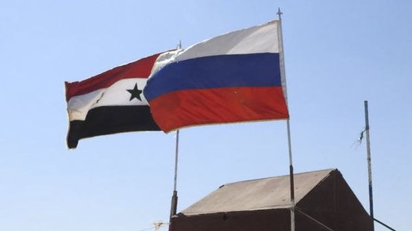Сирийский и российский флаг на восточной стороне гуманитарного коридора Абу Духур в сирийской провинции Идлиб - Sputnik Азербайджан