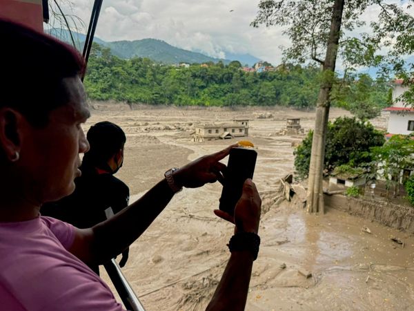 Люди фотографируют и снимают на видео вышедшую из берегов и заваленную обломками реку Тришули после внезапного наводнения в непальском округе Нувакот, среда, 26 августа 2026 года.(AP Photo/Niranjan Shrestha) - Sputnik Азербайджан