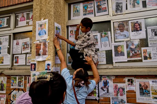 Женщина помогает мальчику закрепить на стене фотографию их пропавшего родственника рядом со снимками других пропавших без вести и погибших людей, выставленными у здания государственной больницы в Катманду, Непал, воскресенье, 30 августа 2026 года(AP Photo/Dar Yasin) - Sputnik Азербайджан