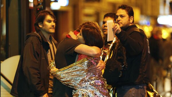 People hug each other before being evacuated by bus, near the Bataclan concert hall in central Paris - Sputnik Азербайджан