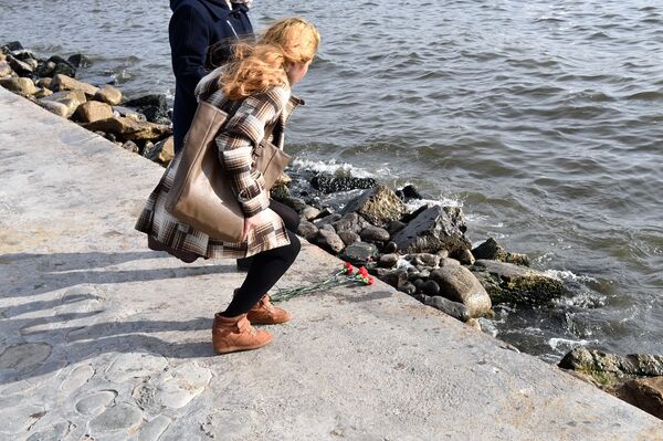 Женщина возлагает гвоздики вдоль берега Каспия - Sputnik Азербайджан