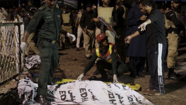 Rescue workers move a body from the site of a blast outside a public park in Lahore, Pakistan - Sputnik Azərbaycan