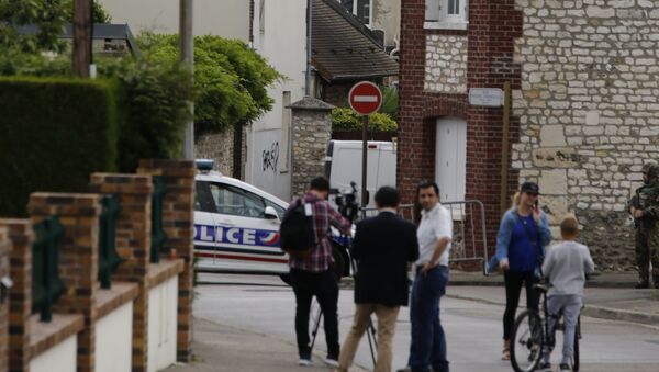 This photo taken on July 26, 2016 shows behind the church ofSaint-Etienne-du-Rouvray, blocked by police following an attack by two knife-wielding men. French President Francois Hollande that two men who attacked a church and slit the throat of a priest had claimed to be from Daesh, using the Arabic name for the Islamic State group. - Sputnik Azərbaycan