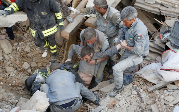 Спасатели вытаскивают из руин пострадавшего во время землетрясения в Италии - Sputnik Азербайджан
