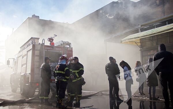 Пожарные и сотрудники торгового центра у входа в здание, которое практически полностью было уничтожено пожаром - Sputnik Азербайджан