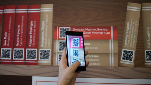 Девушка сканирует QR-код на презентации проекта Мобильные библиотеки, фото из архива - Sputnik Азербайджан