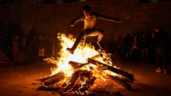 Мужчина прыгает через костер во время празднования вторника огня в Баку - Sputnik Azərbaycan