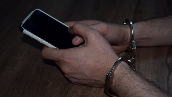 Мужчина в наручниках с телефоном в руке, фото из архива - Sputnik Azərbaycan