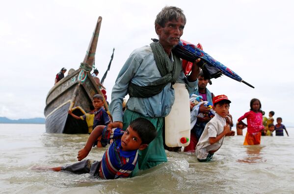 Мужчина из народности рохинджа вытаскивает ребенка из воды после пересечения границы Бангладеш через Бенгальский залив - Sputnik Азербайджан