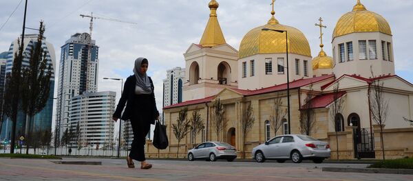Женщина в хиджабе проходит по улице рядом с православной церковью Архангела Михаила на проспекте имени Ахмата Кадырова в Грозном, фото из архива Женщина в хиджабе проходит по улице рядом с православной церковью Архангела Михаила на проспекте имени Ахмата Кадырова в Грозном, фото из архива - Sputnik Азербайджан